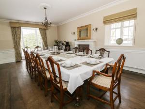 a large dining room with a white table and chairs at Plas Yolyn in Ifton Heath