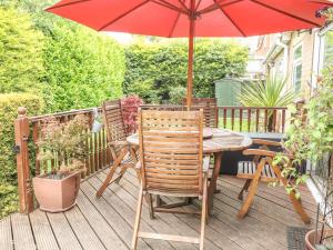 a wooden deck with a table and a red umbrella at Brayton Retreat in Brayton