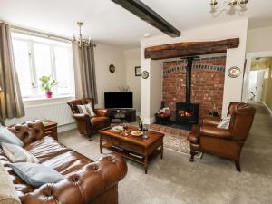 a living room with leather furniture and a fireplace at Plas Yolyn in Ifton Heath