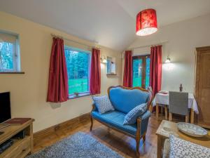 a living room with a blue chair and a table at Woodpeckers Cottage in Church Stretton