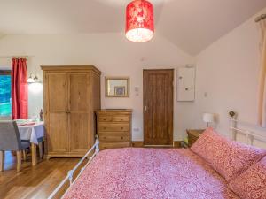 a bedroom with a pink bed and a table at Woodpeckers Cottage in Church Stretton