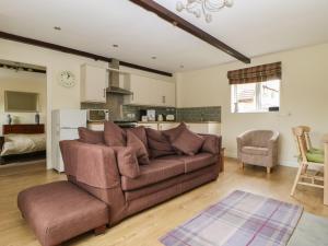 a living room with a brown couch and a kitchen at The Paddock in Wheldrake