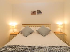 Un dormitorio con una cama blanca con dos lámparas. en 6 Malthouse Court, en Saint Decumans