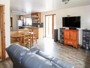 a living room with a leather couch and a table at Dragonfly Lodge in Yaxham