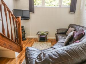 a living room with a leather couch and a tv at End Retreat in Ashmanhaugh