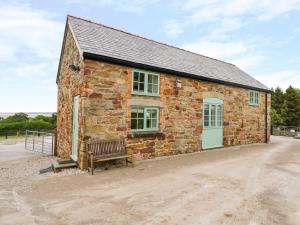 ein Backsteingebäude mit einer Bank davor in der Unterkunft Plas Tirion Cottage in Mostyn