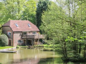 una casa sentada en el agua con un estanque en Miswells Cottages - Lake View, en Turners Hill