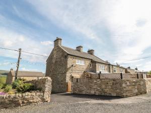 an old stone house with a stone fence at Belgrave House in Mickleton