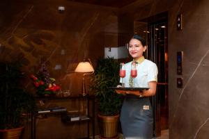 a woman holding a tray with wine glasses on it at Yu Hotel, Candolim in Candolim