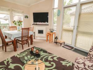 uma sala de estar com uma mesa e uma televisão em Little Gem Lodge em Saint Boswells