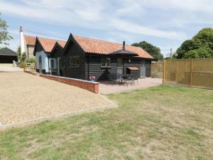 a detached house with a patio and a fence at Whitehands Farm Barn in Old Buckenham