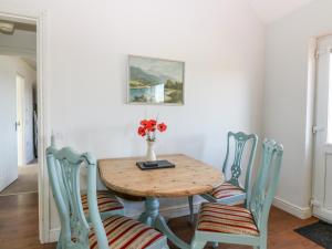 stół jadalny z krzesłami i wazon kwiatów w obiekcie Poppies Cottage w mieście Craignure