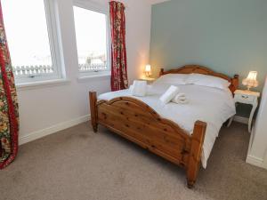 a bedroom with a bed with white sheets and pillows at Poppies Cottage in Craignure