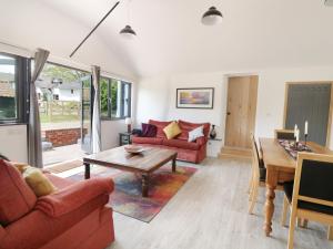 sala de estar con muebles de color rojo y mesa en Whitehands Farm Barn, en Old Buckenham