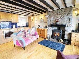 a living room with a couch and a stone fireplace at Jasmin Cottage in Conwy