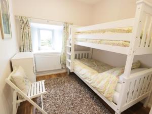 a bedroom with two bunk beds and a chair at Drumbuie in Kirkbean