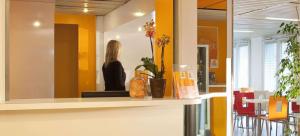 een vrouw staat achter een toonbank in een kamer bij FAST HOTEL Les Ulis - Courtabœuf in Les Ulis