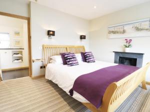 a bedroom with a bed with purple pillows and a fireplace at Jasmin Cottage in Conwy