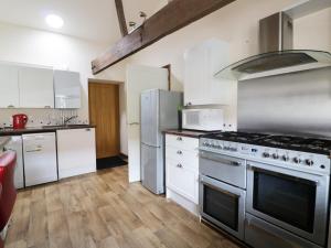 a kitchen with stainless steel appliances and white cabinets at Duckling Barn in Bacton