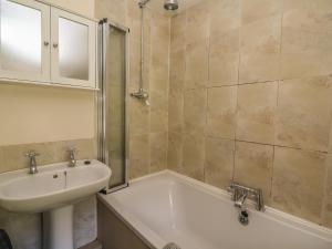 een badkamer met een wastafel en een bad en een wastafel bij Preacher's Cottage in Llanbadarn-fynydd