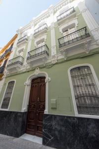 - un bâtiment vert avec une porte en bois et 2 balcons dans l'établissement Céntriko Apartments Quintero 40, à Séville
