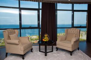 two chairs and a table in a room with windows at Euphoria Batumi Convention & Casino Hotel in Batumi
