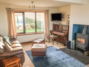 a living room with a couch and a piano at Coast House in Little Gruinard