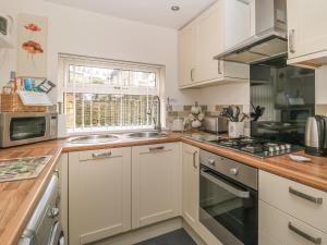 a kitchen with white cabinets and a sink and a window at Worth Valley Cottage in Haworth