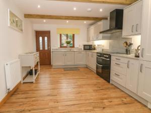 a kitchen with white cabinets and a wooden floor at Caer Moel in Llanwnda