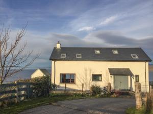 a white house with a black roof and a fence at Coast House in Little Gruinard