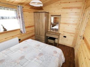 1 dormitorio con 1 cama en una cabaña de madera en Hayfields, en Grimston