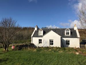 a white house sitting on top of a green field at Half of 6 in The Braes