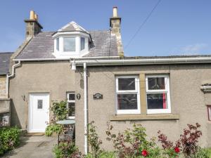 a brick house with a white door and windows at Fishermans Rest in Burghead