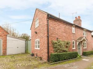 an old brick house with a garage at Borrowers Cottage in Condover