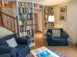 a living room with two chairs and book shelves filled with books at Half of 6 in The Braes