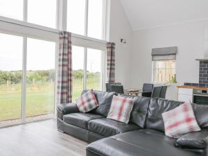a living room with a black leather couch and sliding glass doors at Chance Inn Lodge in Balmedie