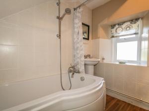 a bathroom with a shower and a tub and a sink at Fishermans Rest in Burghead +17 photos