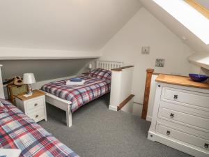 a attic bedroom with two beds and a dresser at Brickfield Cottage in Machynlleth