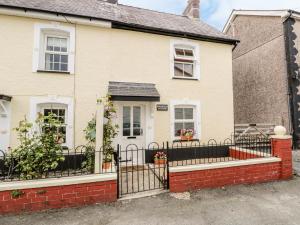 een wit huis met een zwart hek bij Brickfield Cottage in Machynlleth