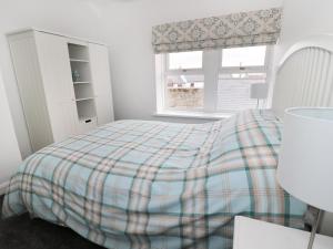 a bedroom with a bed with a plaid blanket at Sunnie Cottage in Seahouses
