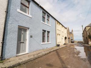 a blue house with a white door on a street at Sunnie Cottage in Seahouses