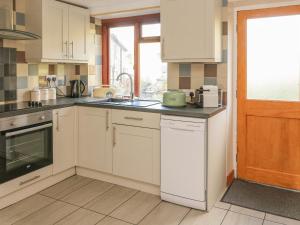 a kitchen with white cabinets and a sink at Lees Cottage in Bradwell