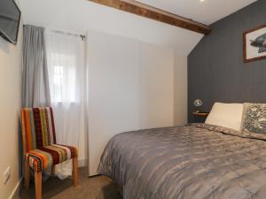 a bedroom with a bed and a window and a chair at The Granary Loft in Sunbrick