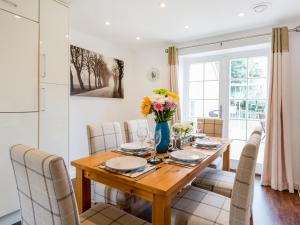 a dining room table with chairs and a vase of flowers at Tus Nua Cottage in Carhampton