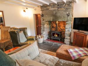 a living room with a stone fireplace and a tv at Bron Olau in Tanygrisiau