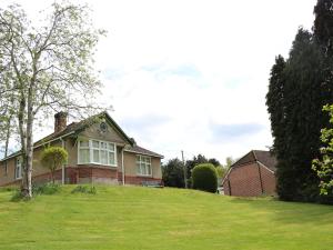 a house on a grassy hill with a tree at Goodrest in Verwood