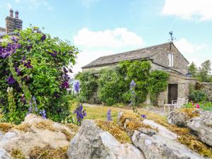 an old stone house with purple flowers in front of it at The Garden Rooms Lawkland in Austwick