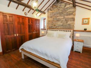 a bedroom with a large bed and a stone wall at Bron Olau in Tanygrisiau