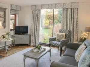 a living room with a couch and a tv at Little Beeches in Selattyn