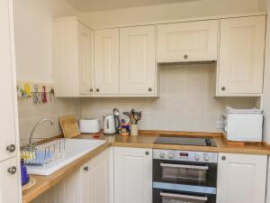 a kitchen with white cabinets and a stove top oven at Butts Hill House in Horton in Ribblesdale